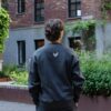 Achterkant zwarte KMKG Crew Sweater, casual look in een stedelijke setting
