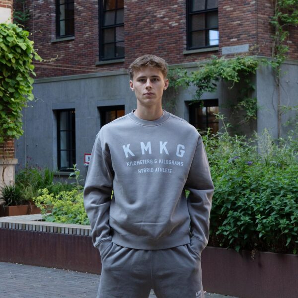 Voorkant grijze KMKG Crew Sweater, casual look in een stedelijke setting