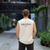 Model draagt de witte KMKG Tank met opdruk 'hybrid athlete', casual look in een stedelijke setting